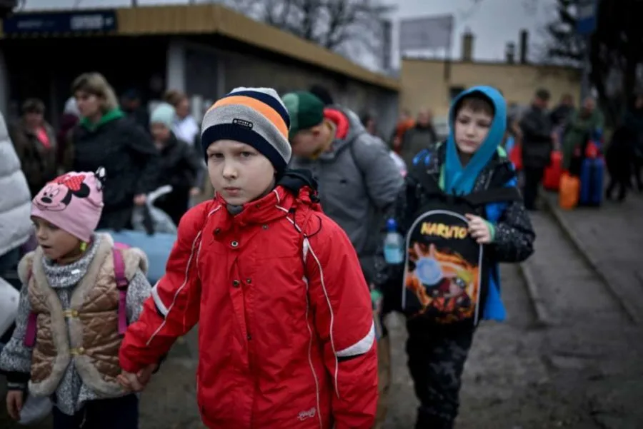 Niños ucranianos con mochilas en un punto de tránsito durante el traslado desde zonas ocupadas.