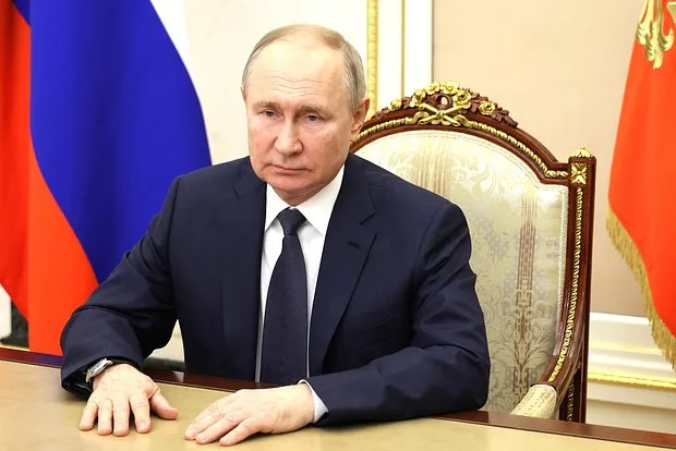 Vladímir Putin en su mesa de trabajo ante una bandera rusa; la Corte Penal Internacional ha dictado una orden en su contra por la deportación de niños ucranianos.